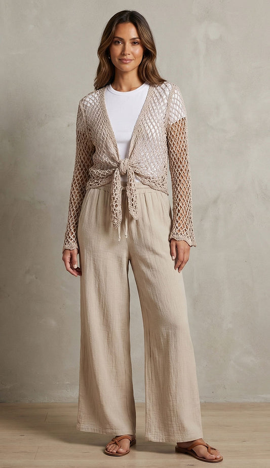 Woman wearing milio milano linen pants with crochet top over a white tee a against a neutral background.