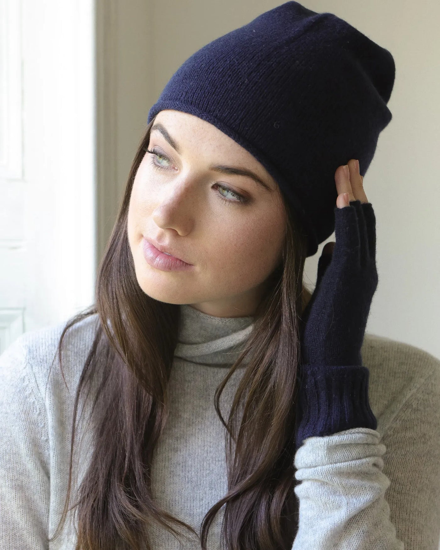 Woman wearing a indigo navy blue beanie and matching gloves indoors
