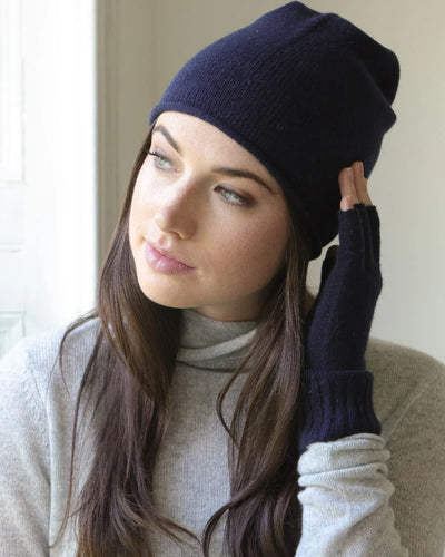 Woman wearing a indigo navy blue beanie and matching gloves indoors