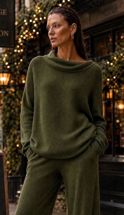 Italian Olive Sweater on a woman wearing  olive pants on a street with white twinkle lights 
