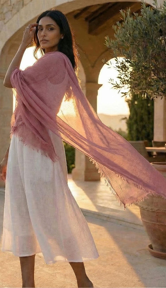 Woman in a white dress with a light pink scarf standing outdoors 