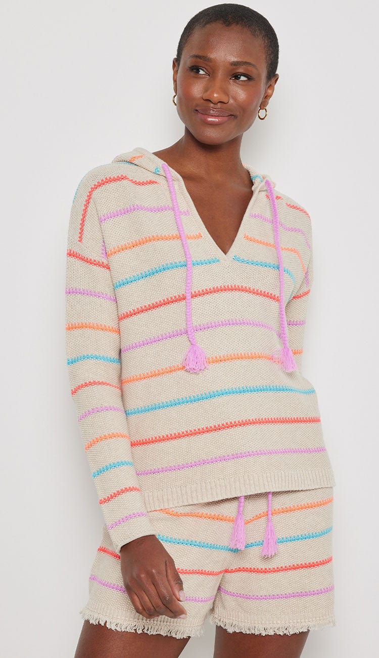 A woman wearing a striped hoodie with a V-neck and attached hood, in colors almond, pink, blue, and yellow, paired with matching shorts.