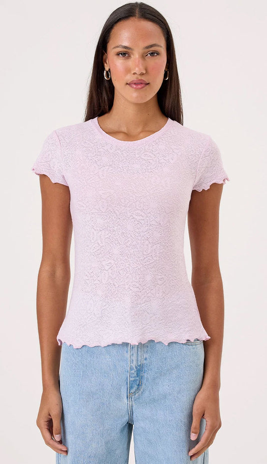 Woman wearing a Goldie Love Story light pink top and blue jeans on a white background