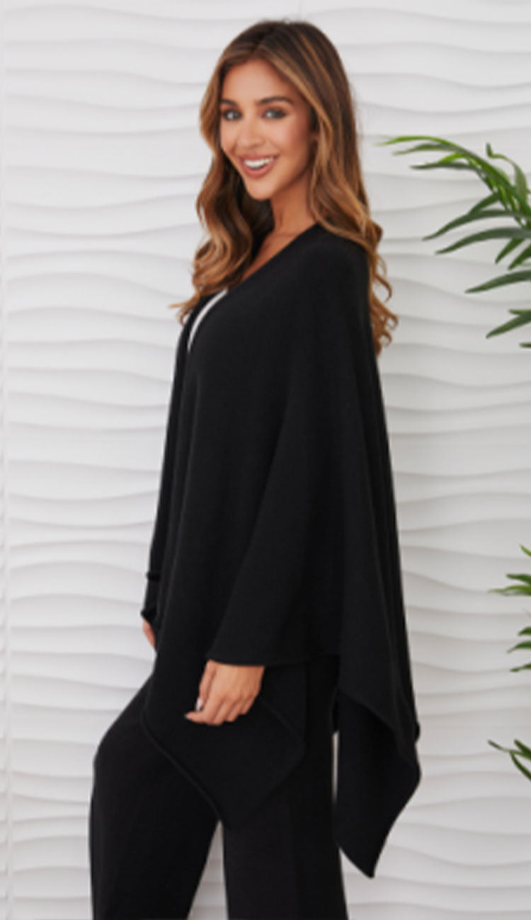 Woman wearing the milio milano knit dolman sleeve open cardigan wrap with black flaire pants and a white tee - side view
