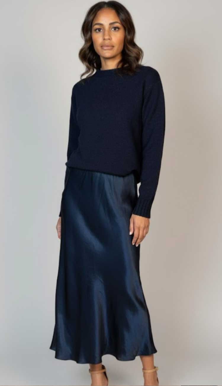 woman wearing a navy sweater and shirt on a grey background