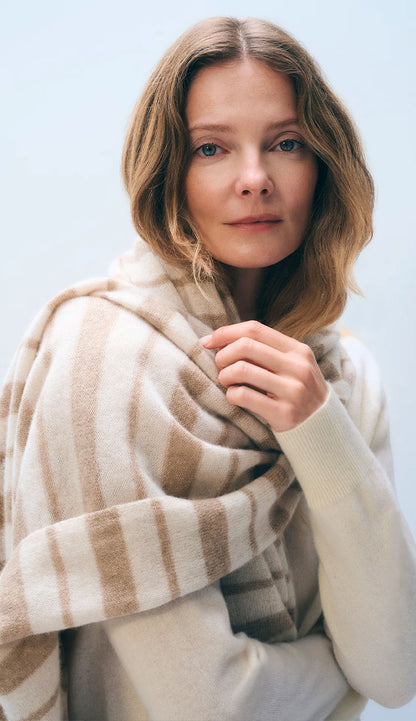 Woman wearing the White and Warren Stripe Scarf in natural and taupe on a grey background.