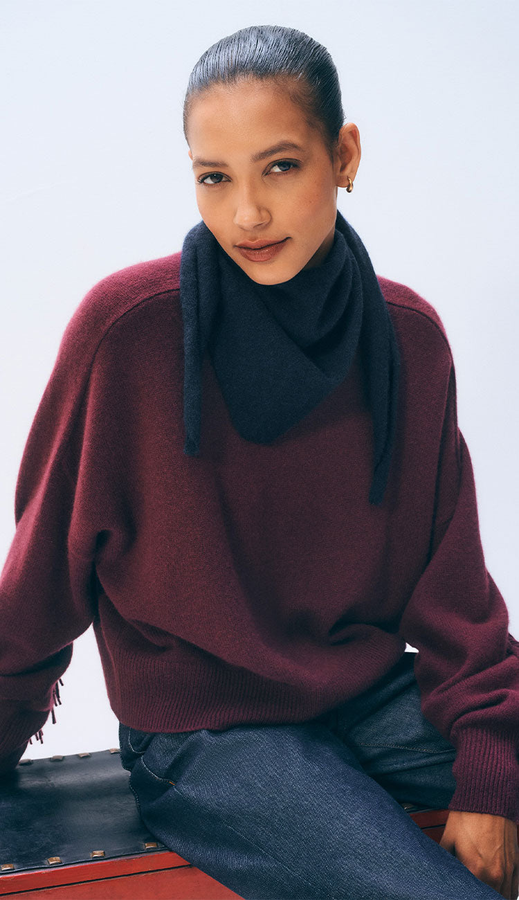 Woman wearing a white and warren cashmere neckerchief mini scarf in dark navy blue on a white background