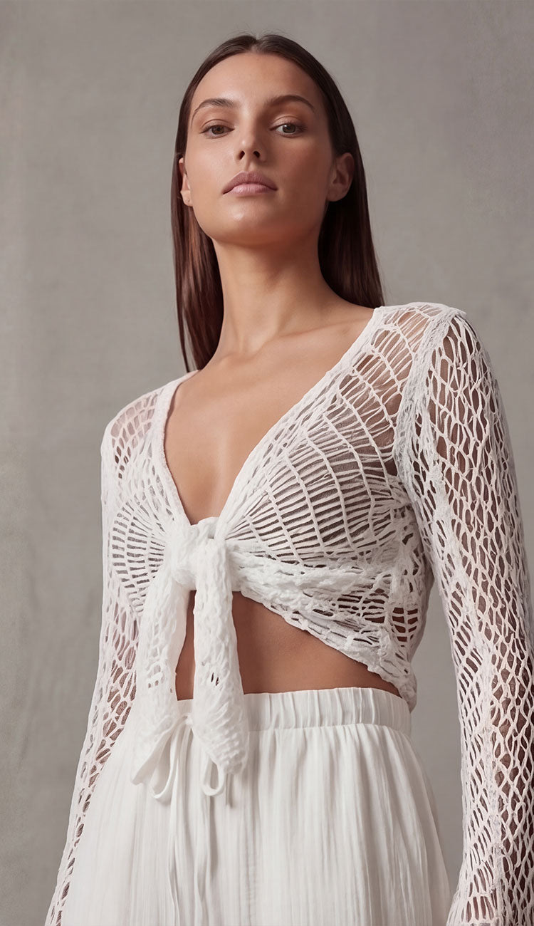 Women wearing a milio milano open knit crochet tie top in white over gauze pants