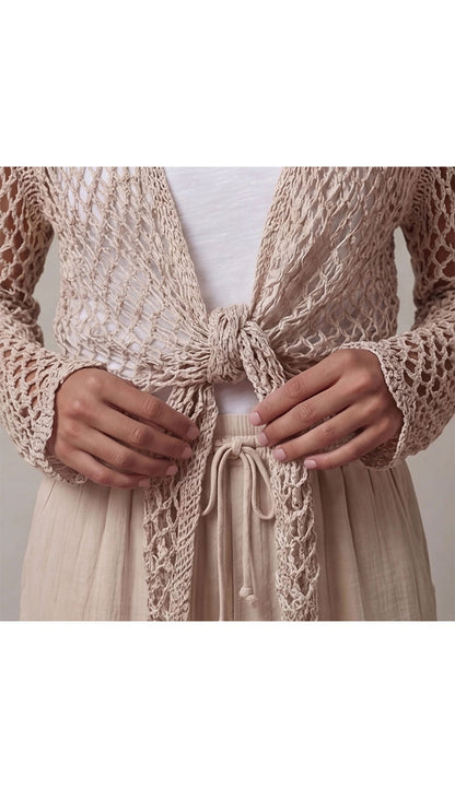 a taupe open crochet top over a white top and beige pants  - detail view
