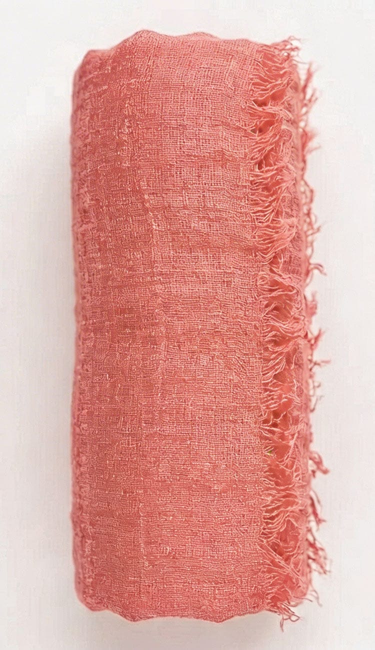salmon pink fabric with frayed edges on a white background