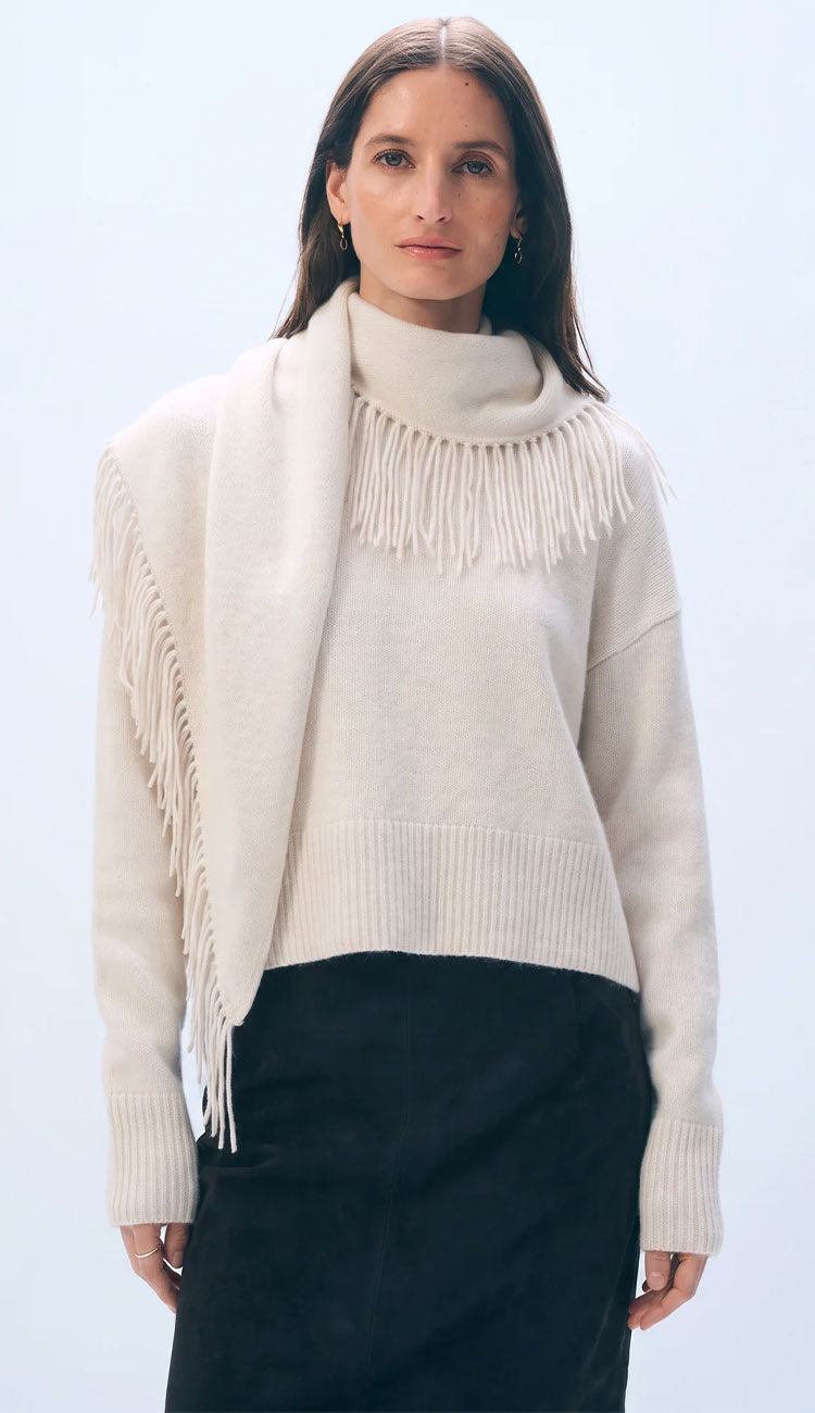 woman wearing an ivory scarf sweater and black skirt on a grey backgound
