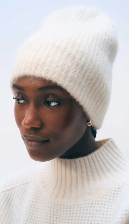 Woman wearing a soft white cashmere beanie and sweater on a white background