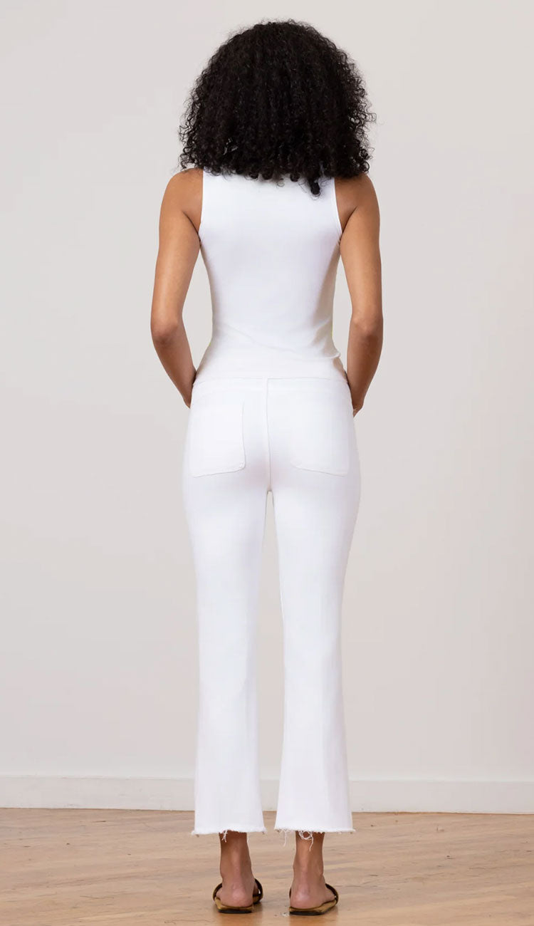 Person wearing a white tee and white jeans avenue montaigne against a plain background