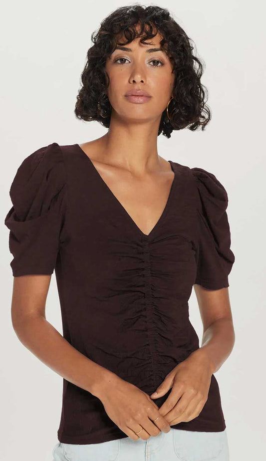 the dutchess t-shirt model wearing a v-neck shirt with puffy sleeves and ruching down the middle in chocolate brown on a white back ground. 