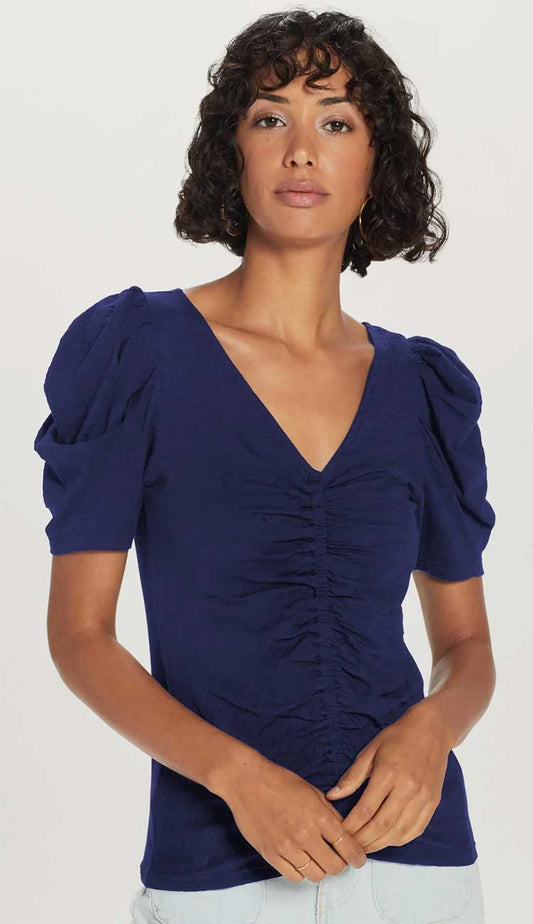the dutchess t-shirt a model wearing a navy t-shirt with puffy sleeves and ruching down the middle on a white background.
