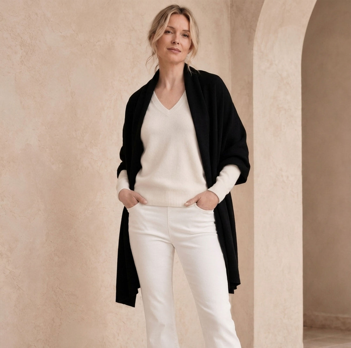 Woman wearing Avenue Montaigne cream pants and an ivory cashmere sweater with a black White & Warren cashmere travel wrap.