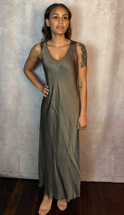 Woman wearing a mocha sleeveless dress against a plain background