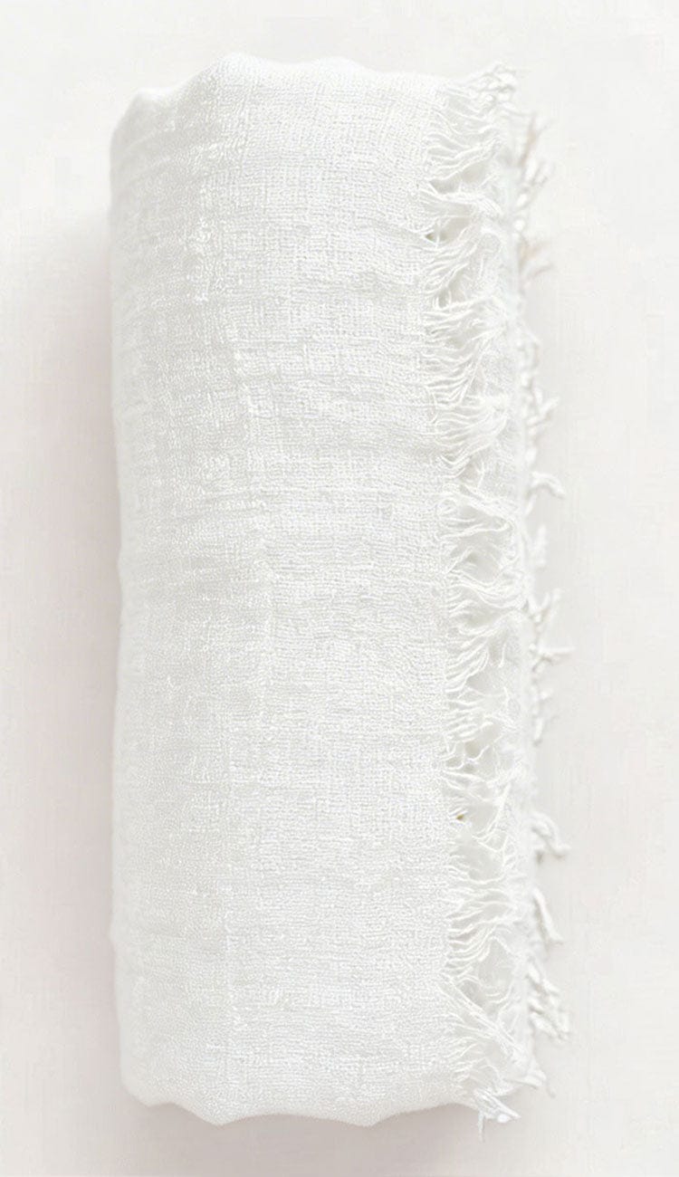White textured fabric with frayed edge on a light pink background